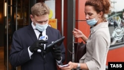 A woman shows a QR code to an employee of McDonald's in downtown Moscow on June 28, 2021, the start of the city's QR-code restrictions for restaurants and cafes.