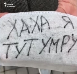 A handmade face mask distributed by Minsk students reads "Ha-ha, I'll die here," in apparent reference to COVID-19 molecules.