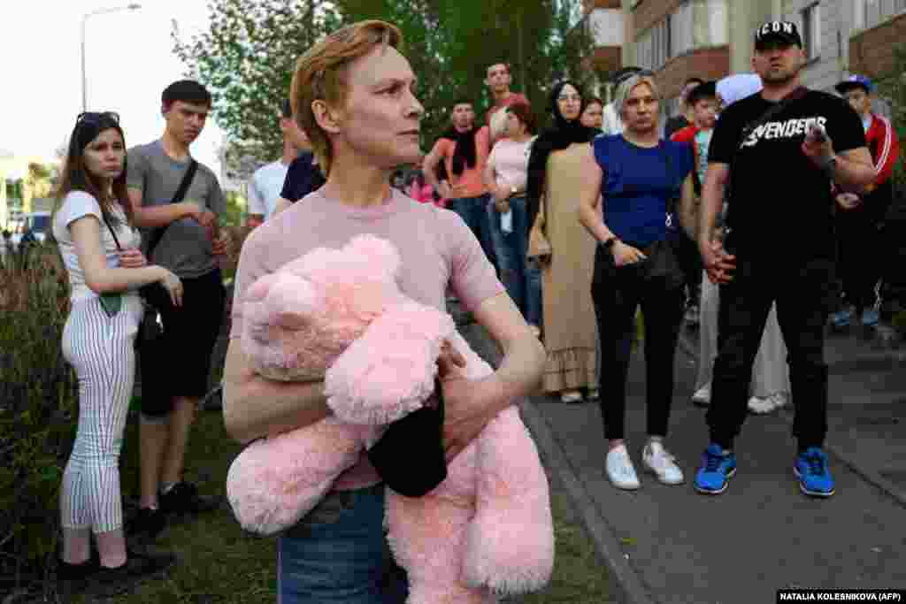 People gather near School No. 175 after the May 11, 2021 shooting there. One woman carries a stuffed animal perhaps either to commemorate the seven children killed in the attack or to donate for the 18 children wounded.&nbsp;