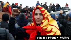A demonstrator wearing the national flag in Bishkek gestures during an October 6, 2020 protest against the results of Kyrgyzstan's parliamentary election.