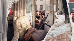 Baku residents on January 21, 1990 examine a bus caught in the attack by Soviet troops.