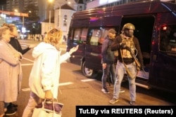 Women address unidentified men holding a baton and possible tear gas gun during protests in Minsk against the presidential inauguration of Alyaksandr Lukashenka on September 23, 2020.