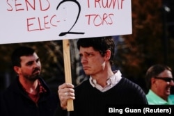 A supporter of U.S. President Donald Trump holds a placard at a "Stop the Steal" protest in Madison, Wisconsin on November 7, 2020, after media announced that Democratic U.S. presidential nominee Joe Biden had won the 2020 U.S. presidential election.