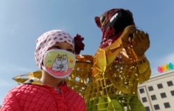 A girl wearing a protective face mask is seen near a masked squirrel installation in Almaty, Kazakhstan after the country declared a state of emergency on March 15, 2020 as an anti-coronavirus measure.