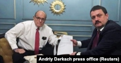 Ukrainian lawmaker Andriy Derkach (right) and U.S. President Donald Trump's personal lawyer, Rudy Giuliani, show a document during an undated meeting in Kyiv.