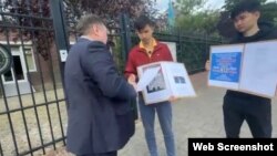 Кымбат Абеуулы (в центре) и Таскын Кудайберген разговаривают с представителем посольства Казахстана во время акции протеста у здания посольства в Амстердаме