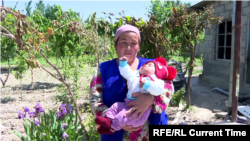 Maylyuda Abdrakhmanova holds her youngest of five children, three months old, near her destroyed house in the Kyrgyz village of Mascat.