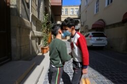 Boys shake hands on a street in Baku, the capital of Azerbaijan,after the introduction of restrictions on leaving the house in order to restrain the spread of COVID-19.