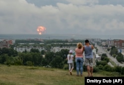 A family watches explosions at a military ammunition depot near the city of Achinsk in eastern Siberia's Krasnoyarsk region on August 5, 2019.