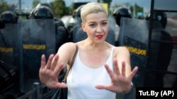 With police to her back, Belarusian opposition leader Maryya Kalesnikava mimes pushing back protesters during a rally in Minsk on August 30, 2020.