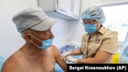A Russian medical worker, right, administers a shot of Russia's Sputnik V coronavirus vaccine on June 18, 2021 in a mobile vaccination center on Sakhalin Island.