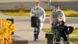 Medical workers push a woman in a wheelchair outside a hospital for patients infected with COVID-19 on the outskirts of Moscow on October 15, 2020. 