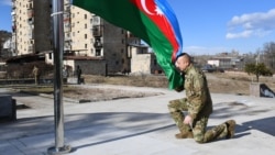 Azerbaijani President Ilham Aliyev kneels in front of the Azerbaijani flag during his visit to the Nagorno-Karabakh town of Shusha on January 15, 2021.