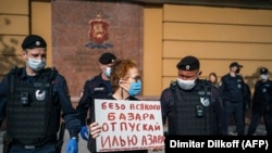Police officers in Moscow detain Russian photographer Viktoria Ivleva during her May 28 solo protest outside of police headquarters in support of jailed journalist and activist Ilya Azar.   "Release Ilya Azar without any fuss," her sign reads. 