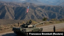 Servicemen from Russian peacekeeping troops stand next to a tank near the Armenian border following the signature of a November 9, 2020 deal to end the military conflict between Azerbaijan and ethnic Armenian forces in the breakaway region of Nagorno-Karabakh. 