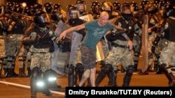 Minsk, Belarus - Law enforcement officers escort a man during clashes with opposition supporters after poll closed at presidential election